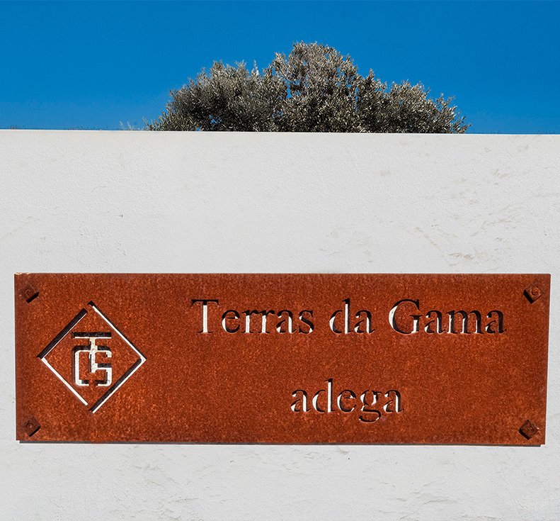 Placa metálica com o logotipo e a inscrição Terras da Gama adega