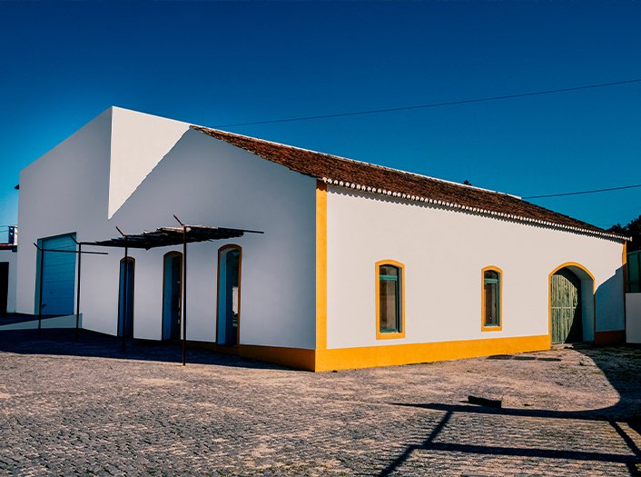 Exterior da adega Terras da Gama, com paredes brancas e contornos amarelos